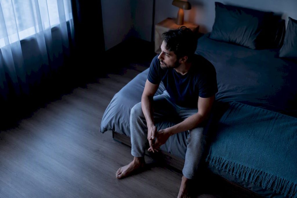Adulto despierto sentado en la cama
